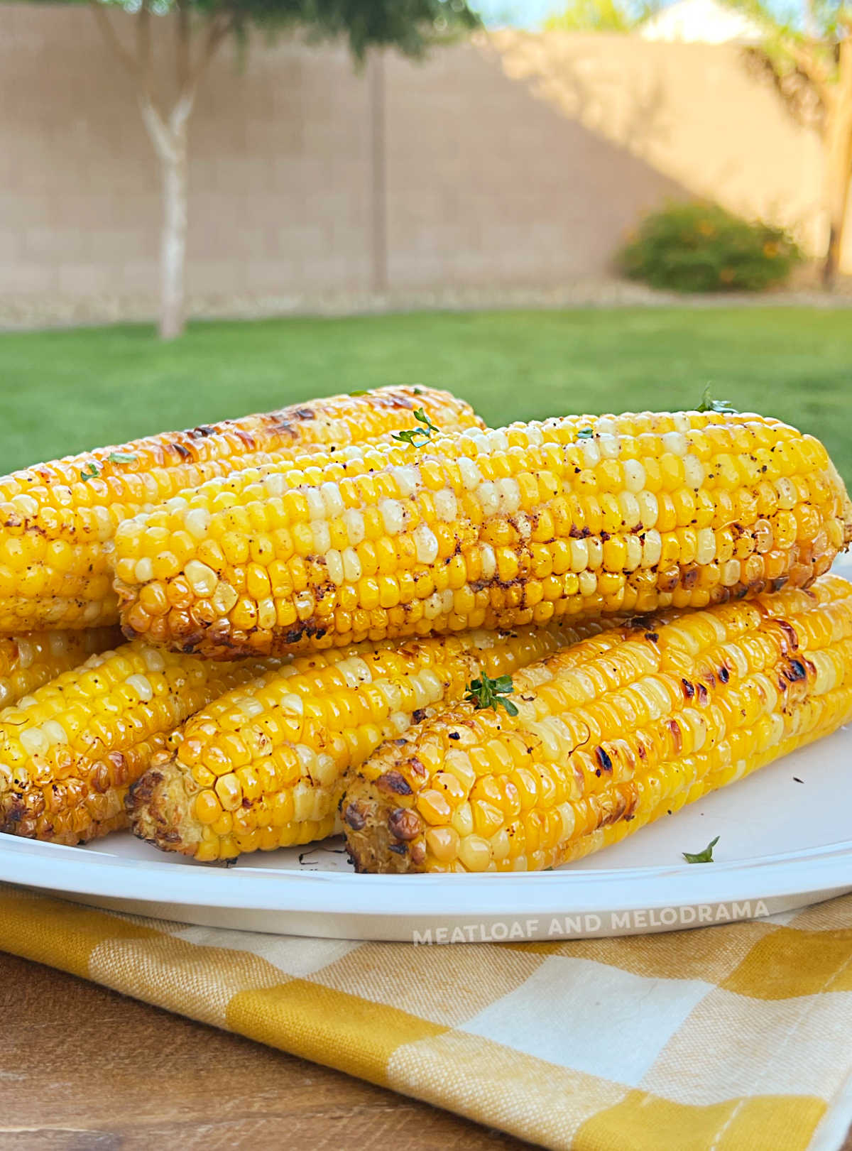 grilled corn on the cob in foil on platter outside by grill