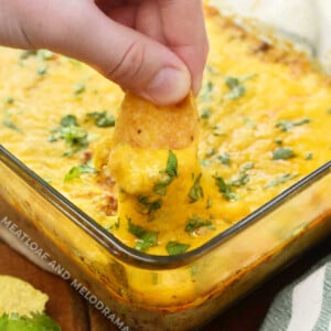 Dip frito chip into baked taco dip recipe with ground beef, cream cheese and cheese