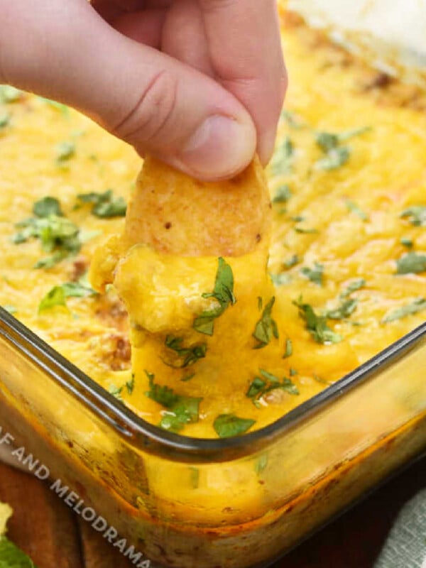 Dip frito chip into baked taco dip recipe with ground beef, cream cheese and cheese