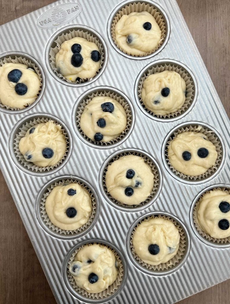 blueberry muffin batter in muffin tin in parchment paper cups