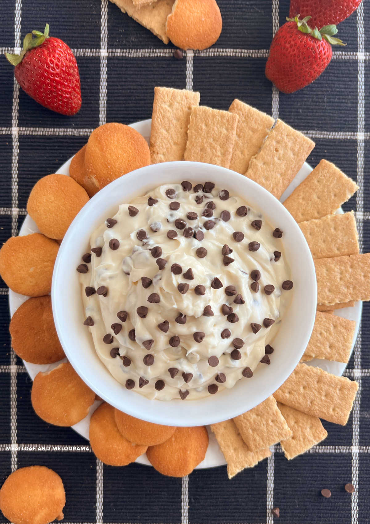 chocolate chip dip with mini chocolate chips in white bowl with graham crackers and cookies