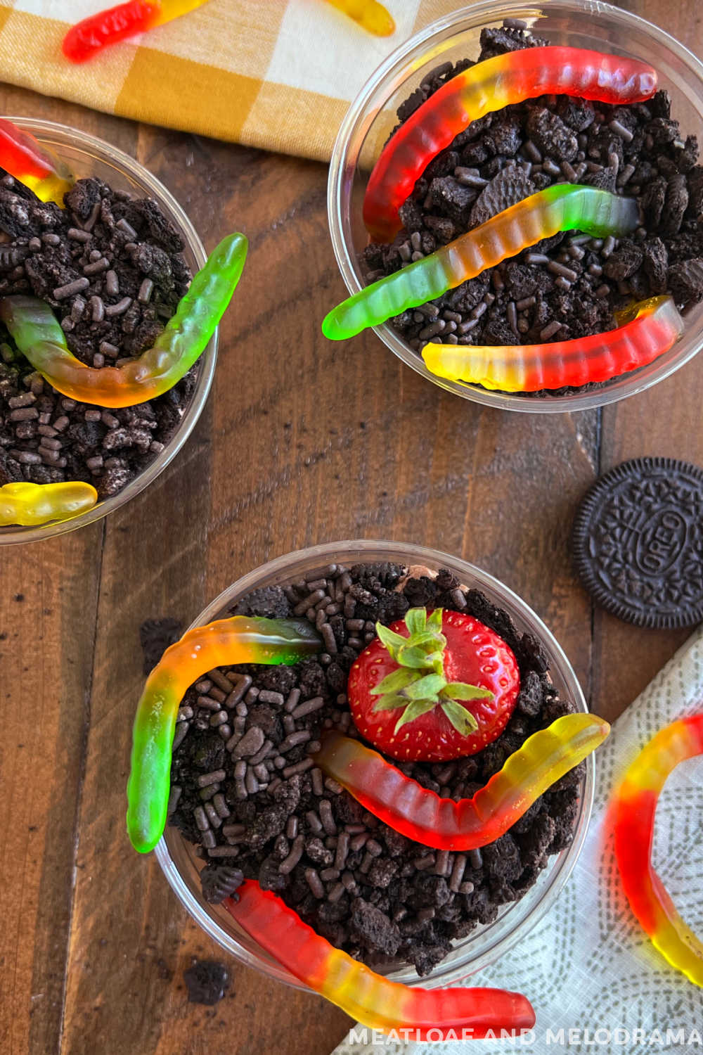 Oreo dirt pie cups with gummy worms and chocolate pudding on table ( mud pie )