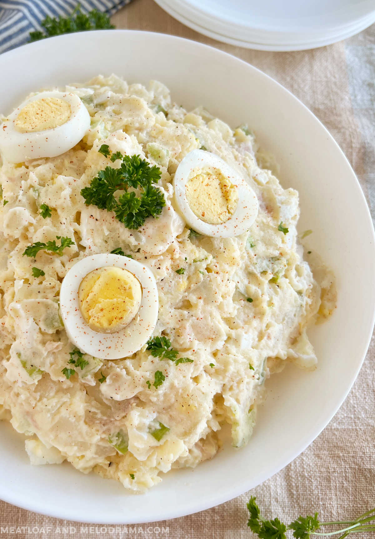 old fashioned potato salad recipe with hard boiled eggs and parsley in white serving bowl