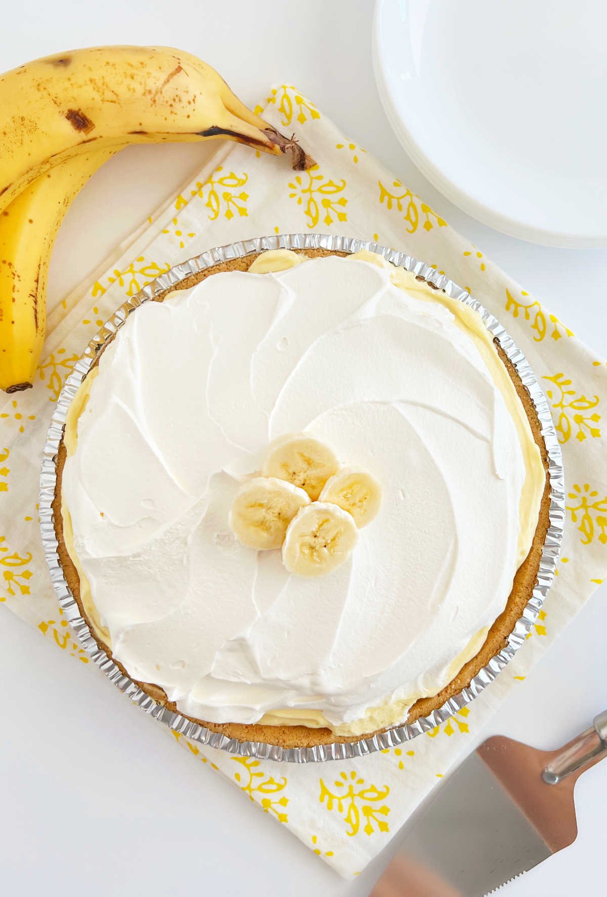 no bake banana pudding pie topped with cool whip and bananas on table