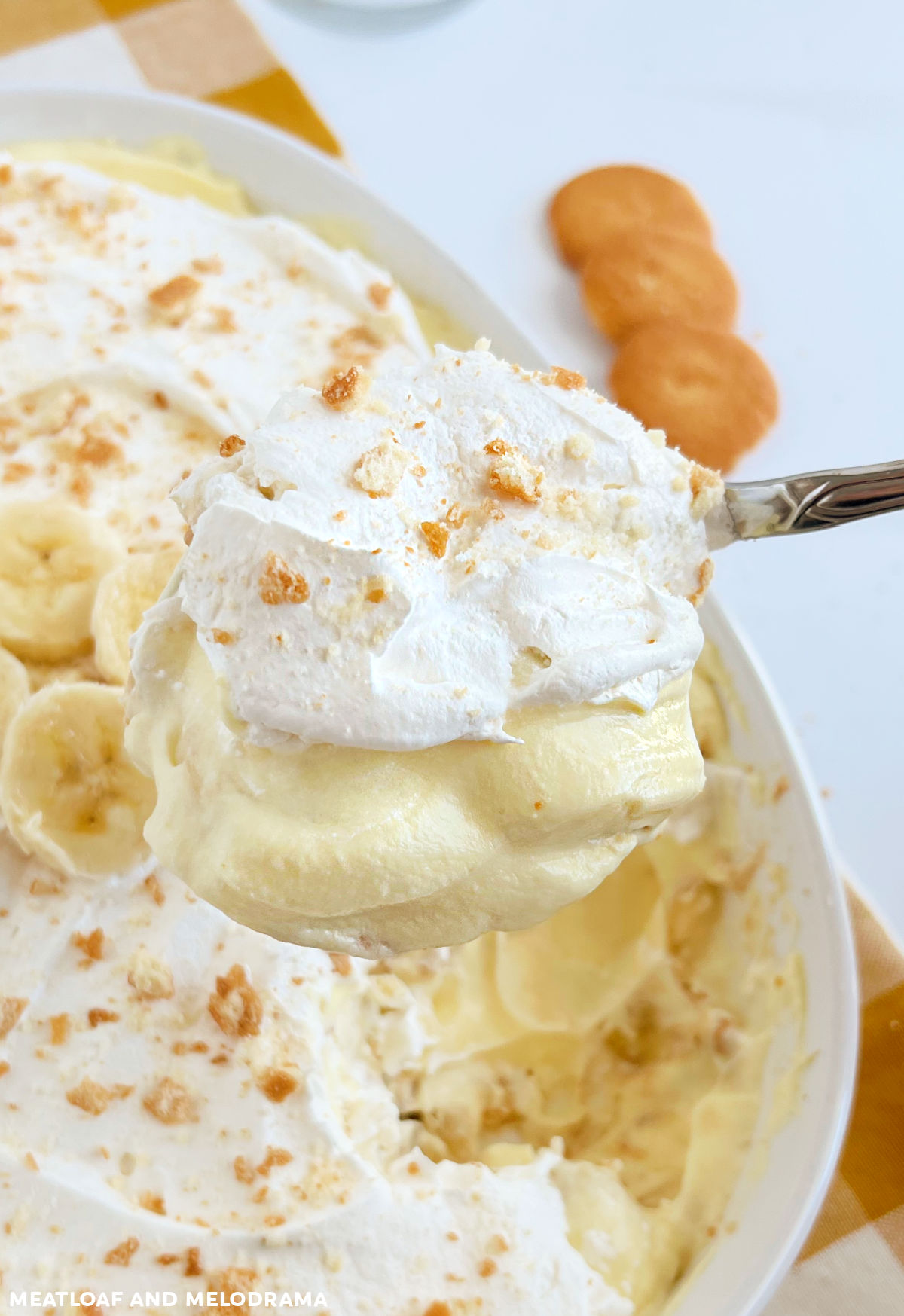 no bake banana pudding with cool whip on a spoon over casserole dish