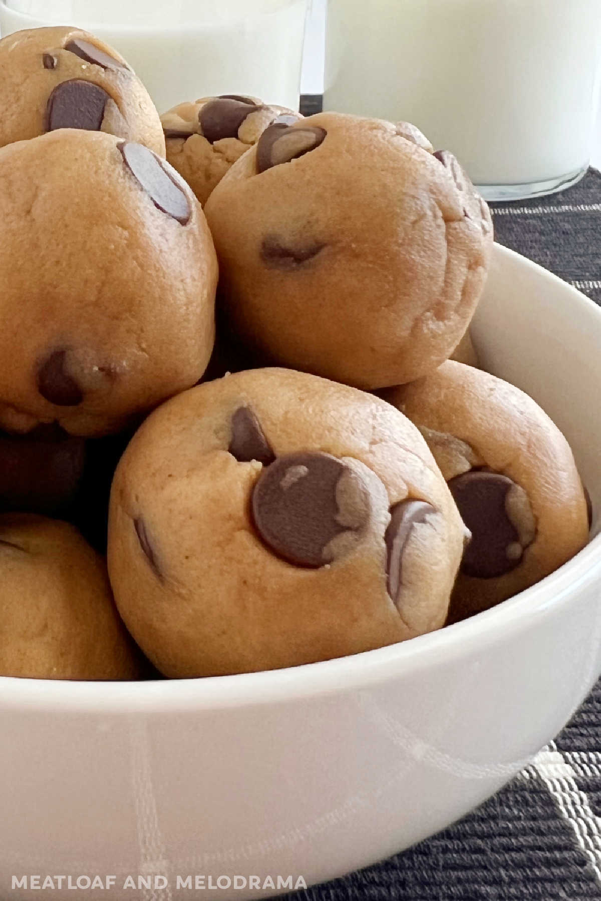 close up of no bake chocolate chip cookie dough balls with milk
