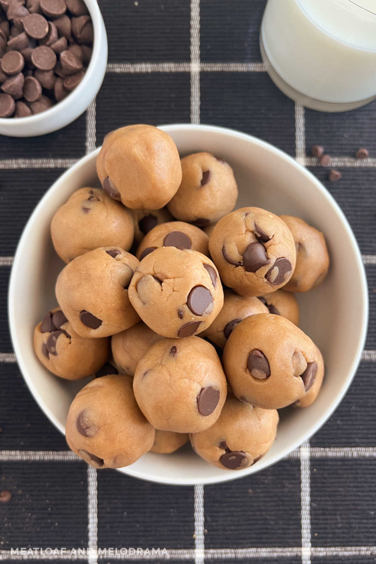 bowl of no bake chocolate chip cookie dough balls with milk on table