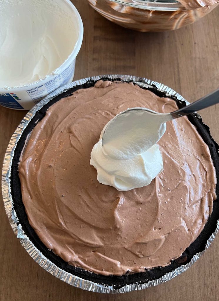 spoon cool whip over chocolate pudding layer in pie crust