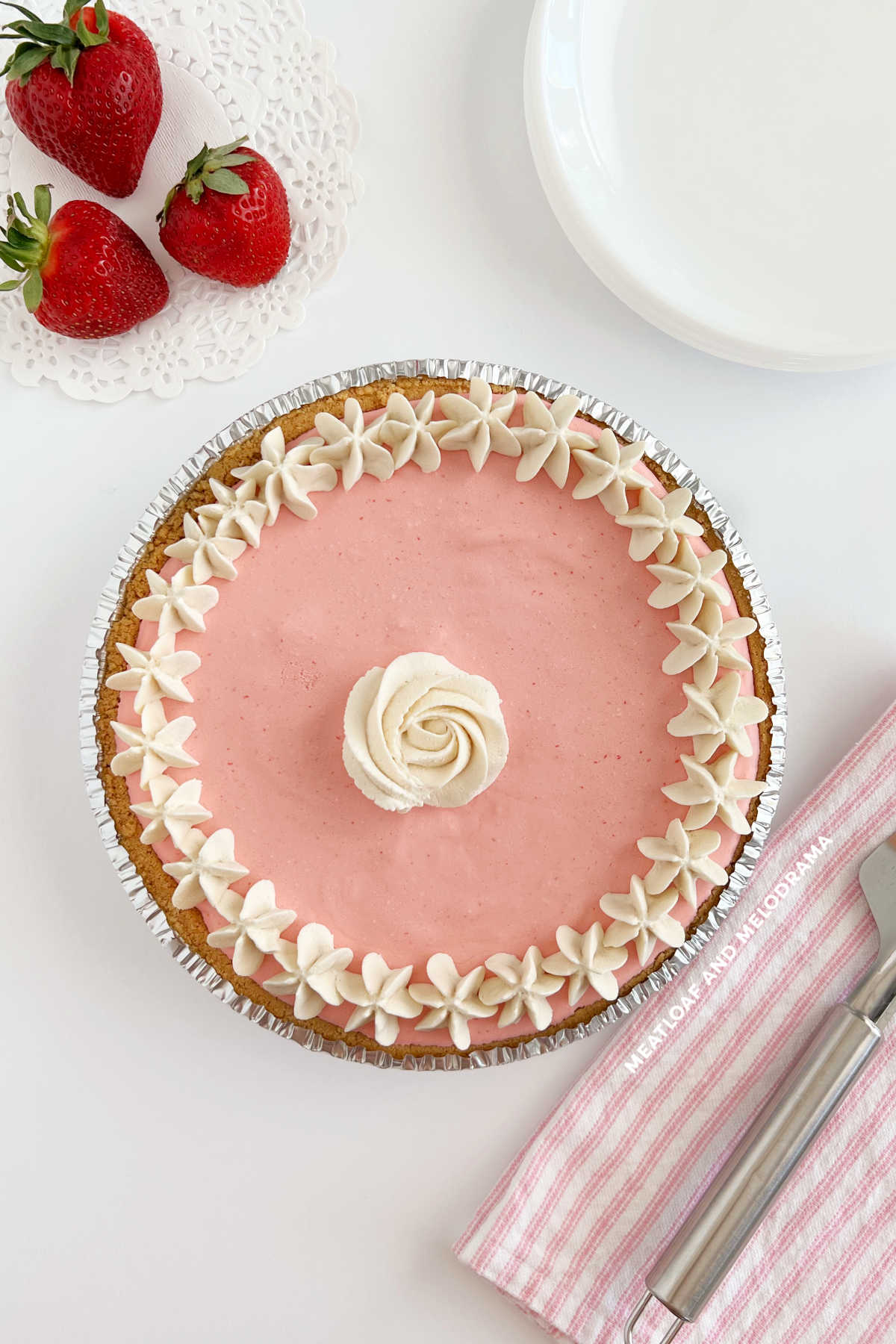 strawberry cool whip pie with strawberries and whipped cream rosette on table
