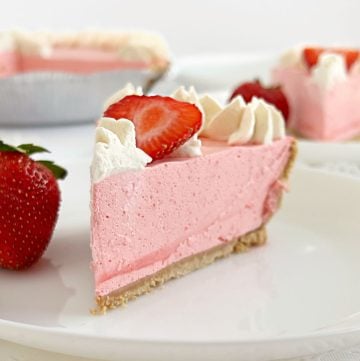 slice of no bake strawberry jello pie with cool whip, fresh strawberries and whipped cream
