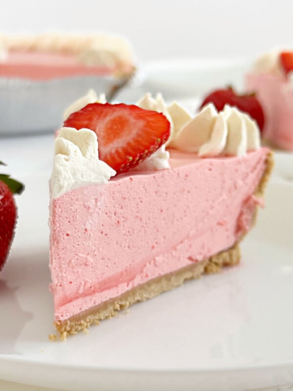 slice of no bake strawberry jello pie with cool whip, fresh strawberries and whipped cream