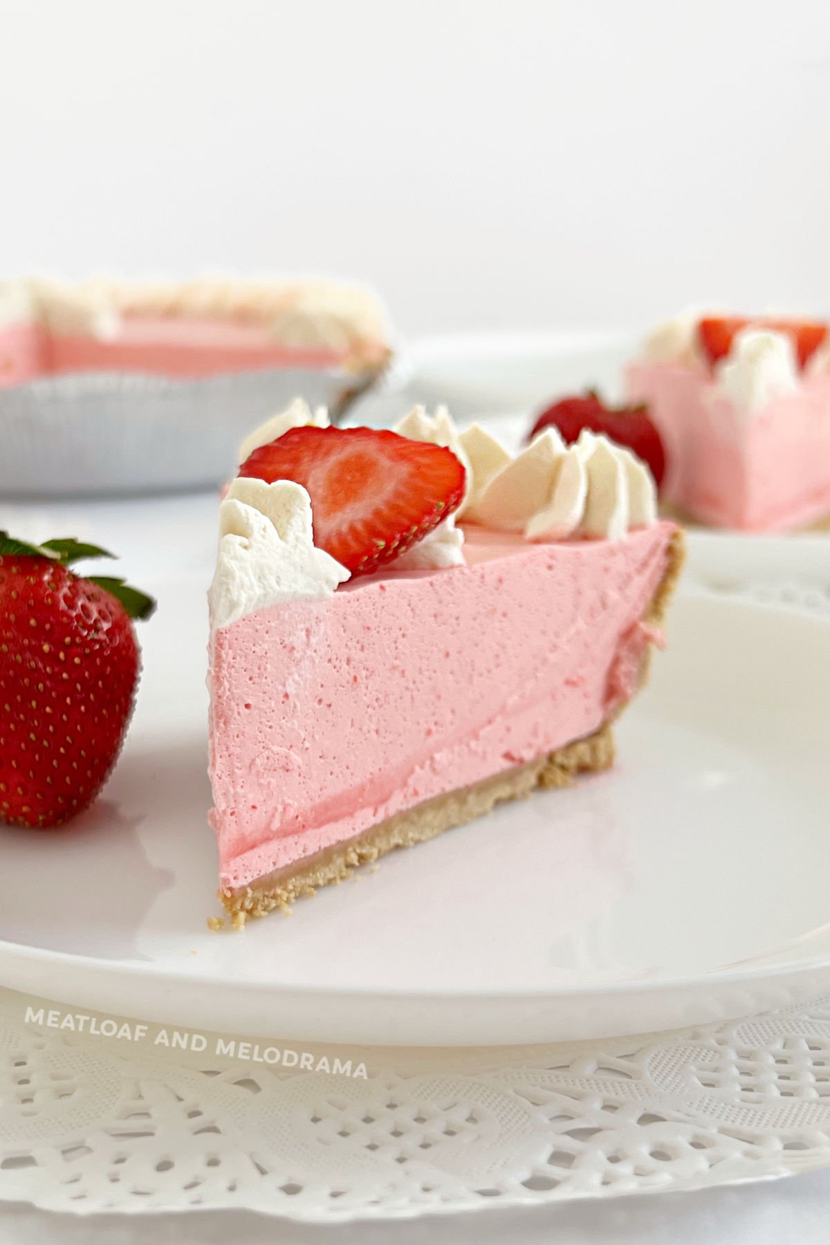 slice of no bake strawberry jello pie with cool whip, strawberries and whipped cream on plate