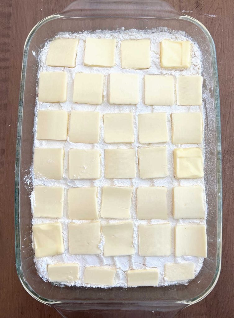 peach dump cake in baking dish with cake mix and butter slices on top