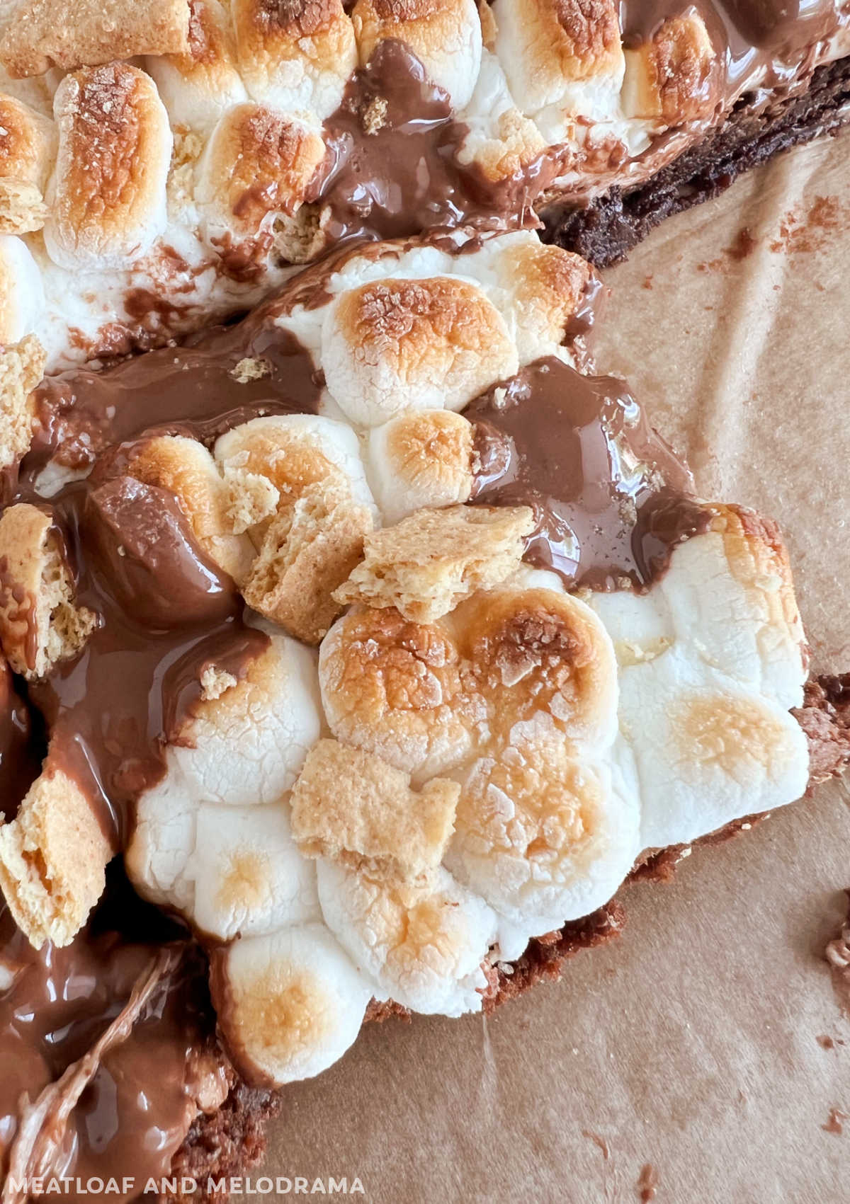 smores brownies topped with toasted marshmallows, graham cracker pieces and melted chocolate bar
