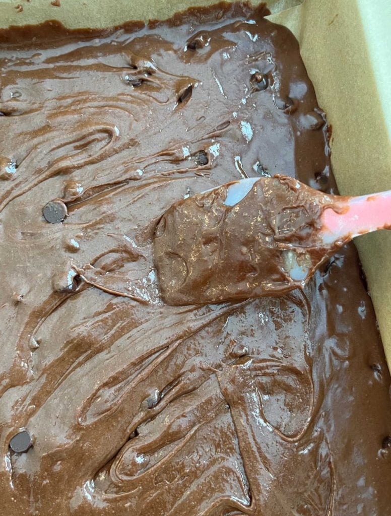 spread brownie batter in parchment paper baking pan