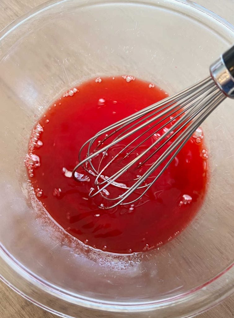 whisk strawberry jello and hot water in mixing bowl