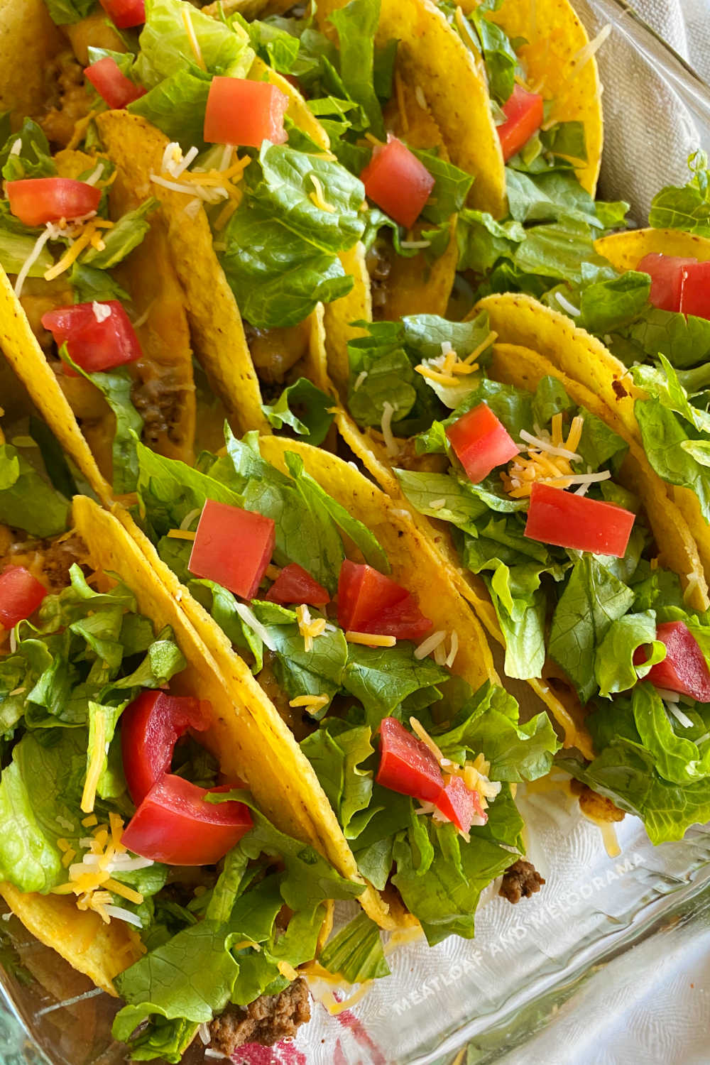 oven baked beef tacos in baking dish with lettuce, tomatoes and cheese