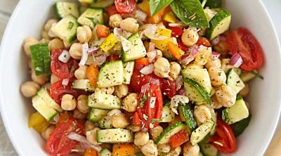 simple chickpea salad with cucumbers, red onion, tomatoes and bell peppers in white bowl