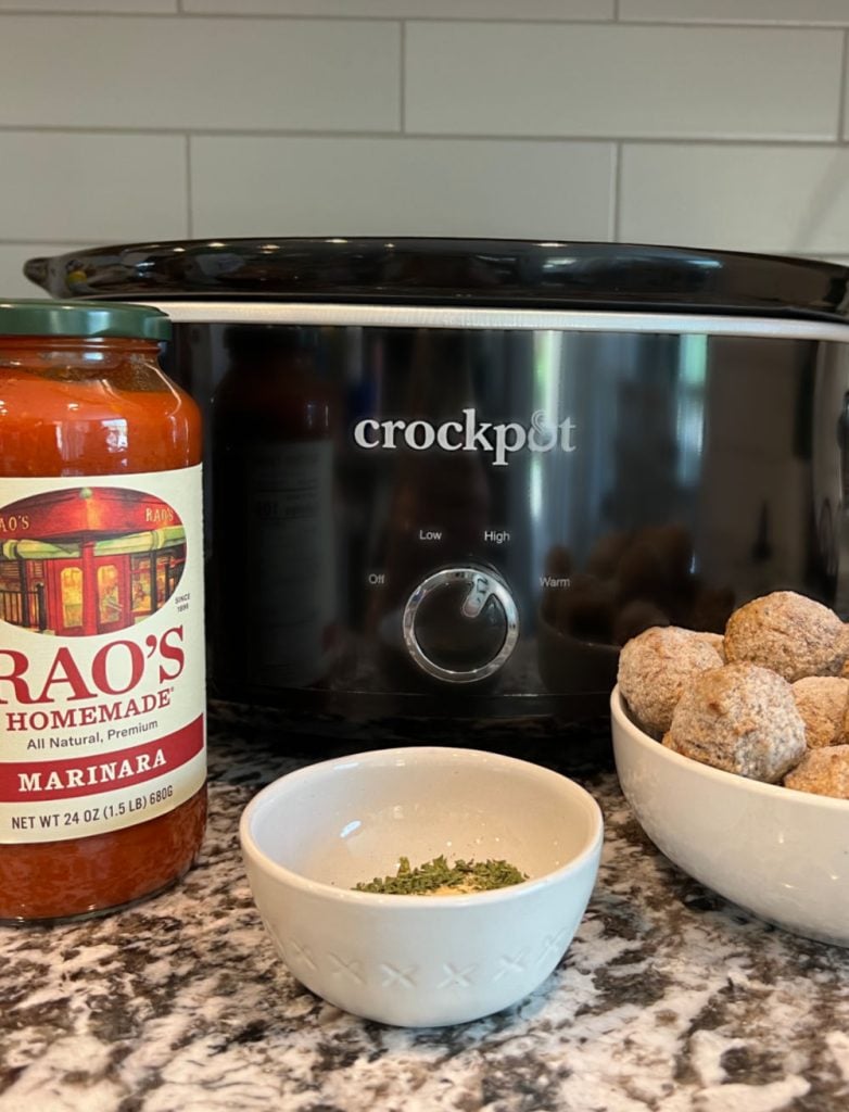 Rao's marinara, crockpot, frozen meatballs and spices on counter