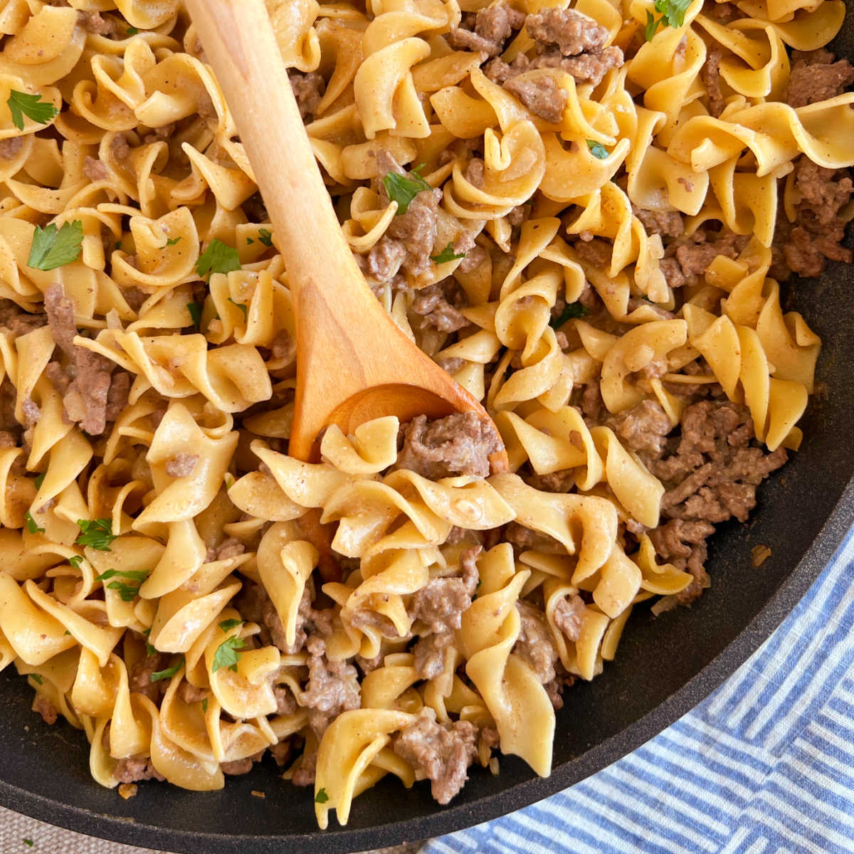 homemade hamburger helper beef stroganoff on wooden spoon in skillet