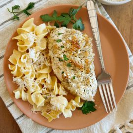 mayo parmesan chicken breast on a plate with egg noodles