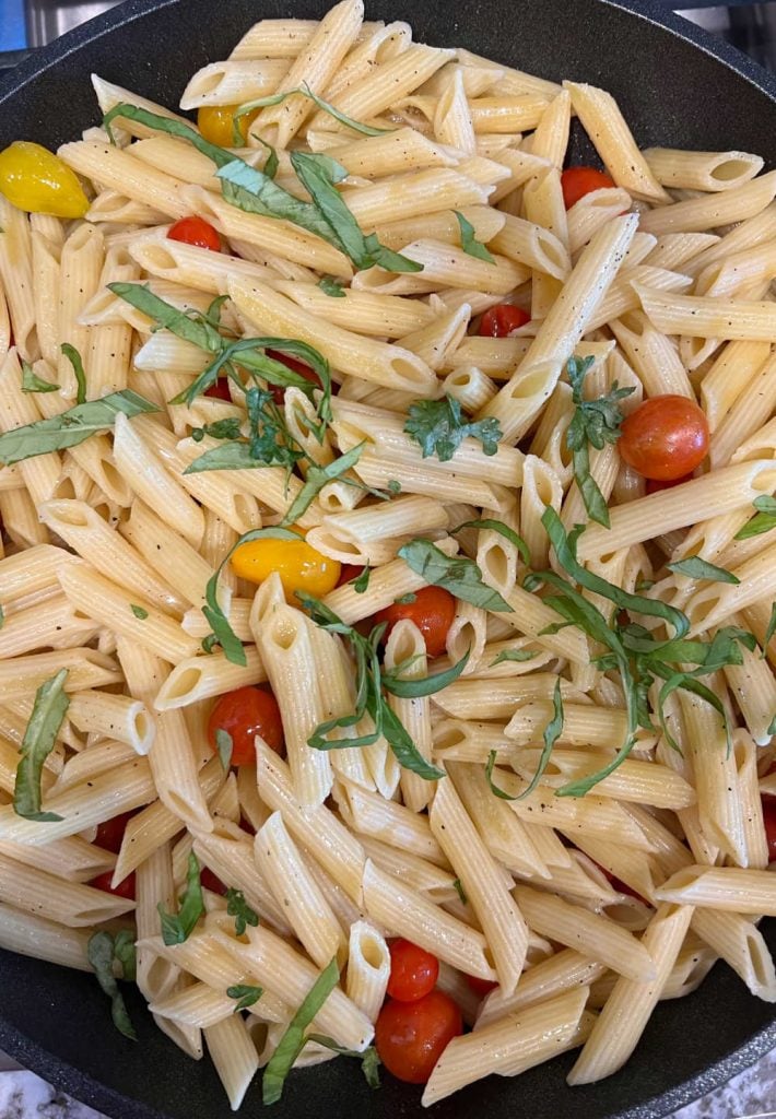 stir penne pasta with fresh basil and cherry tomatoes in skillet