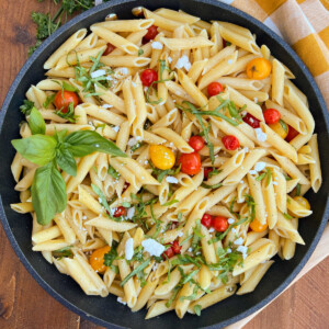penne pasta with grape tomatoes and fresh basil and feta cheese in skillet