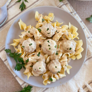 slow cooker swedish meatballs with creamy sauce over egg noodles
