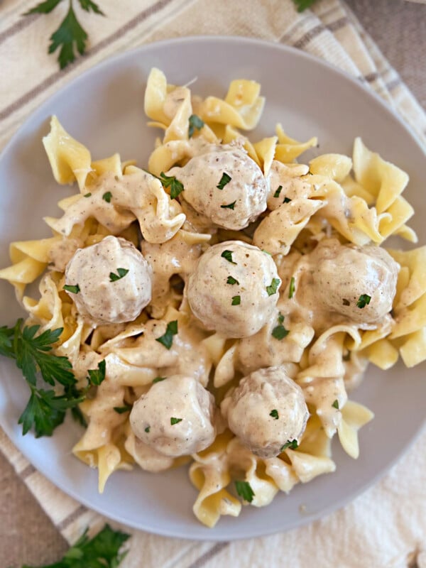 slow cooker swedish meatballs with creamy sauce over egg noodles