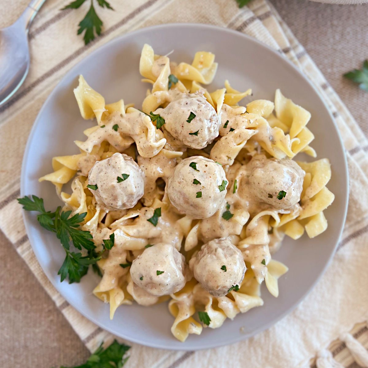 slow cooker swedish meatballs with creamy sauce over egg noodles