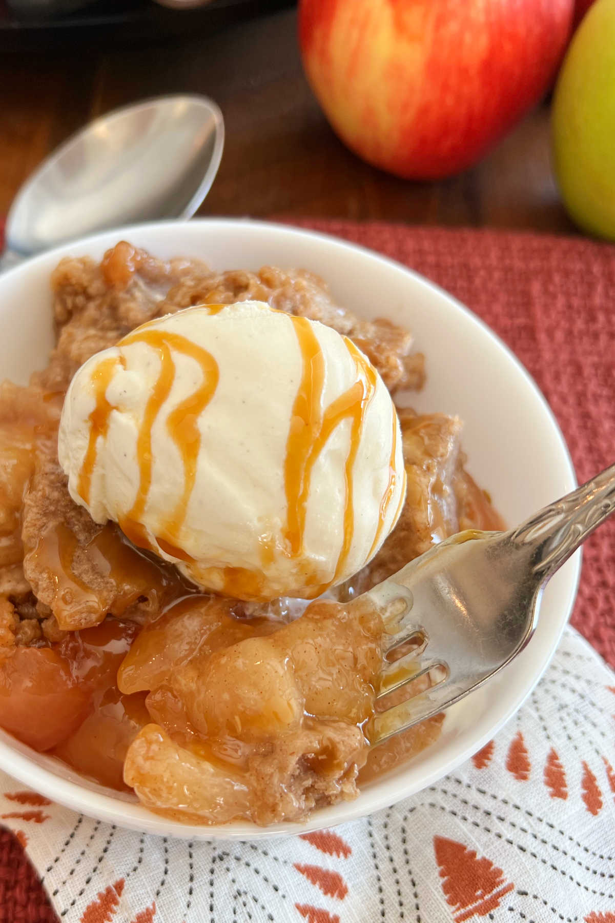 crock pot apple cobbler with ice cream and caramel on fork