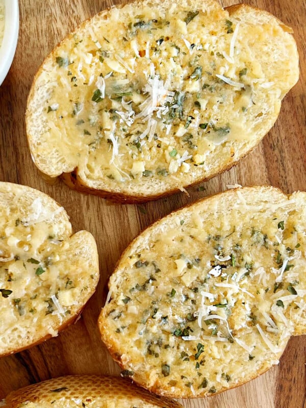 garlic bread slices of with Parmesan cheese and parsley on bread board