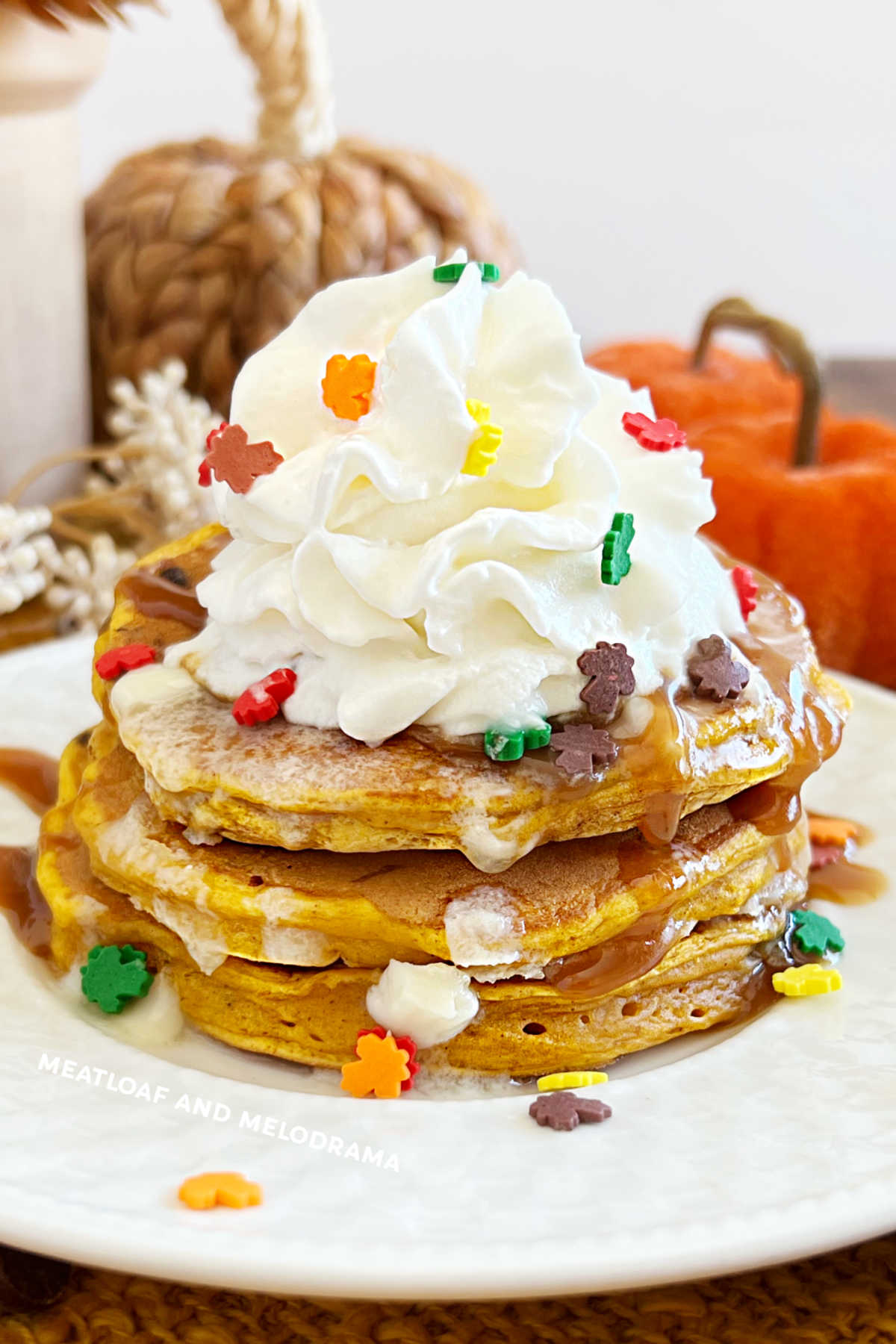stack of homemade pumpkin chocolate chip pancakes with whipped cream on plate