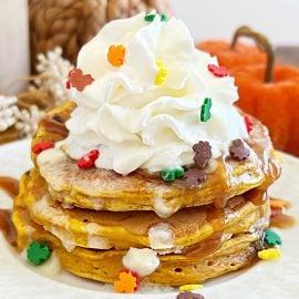 pumpkin chocolate chip pancakes with whipped cream, maple syrup and fall sprinkles