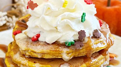 pumpkin chocolate chip pancakes with whipped cream, maple syrup and fall sprinkles
