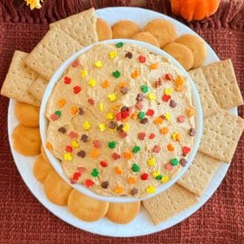pumpkin pie dip with fall sprinkles and cookies in a white bowl