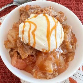 slow cooker apple cobbler with cake mix topping and vanilla ice cream