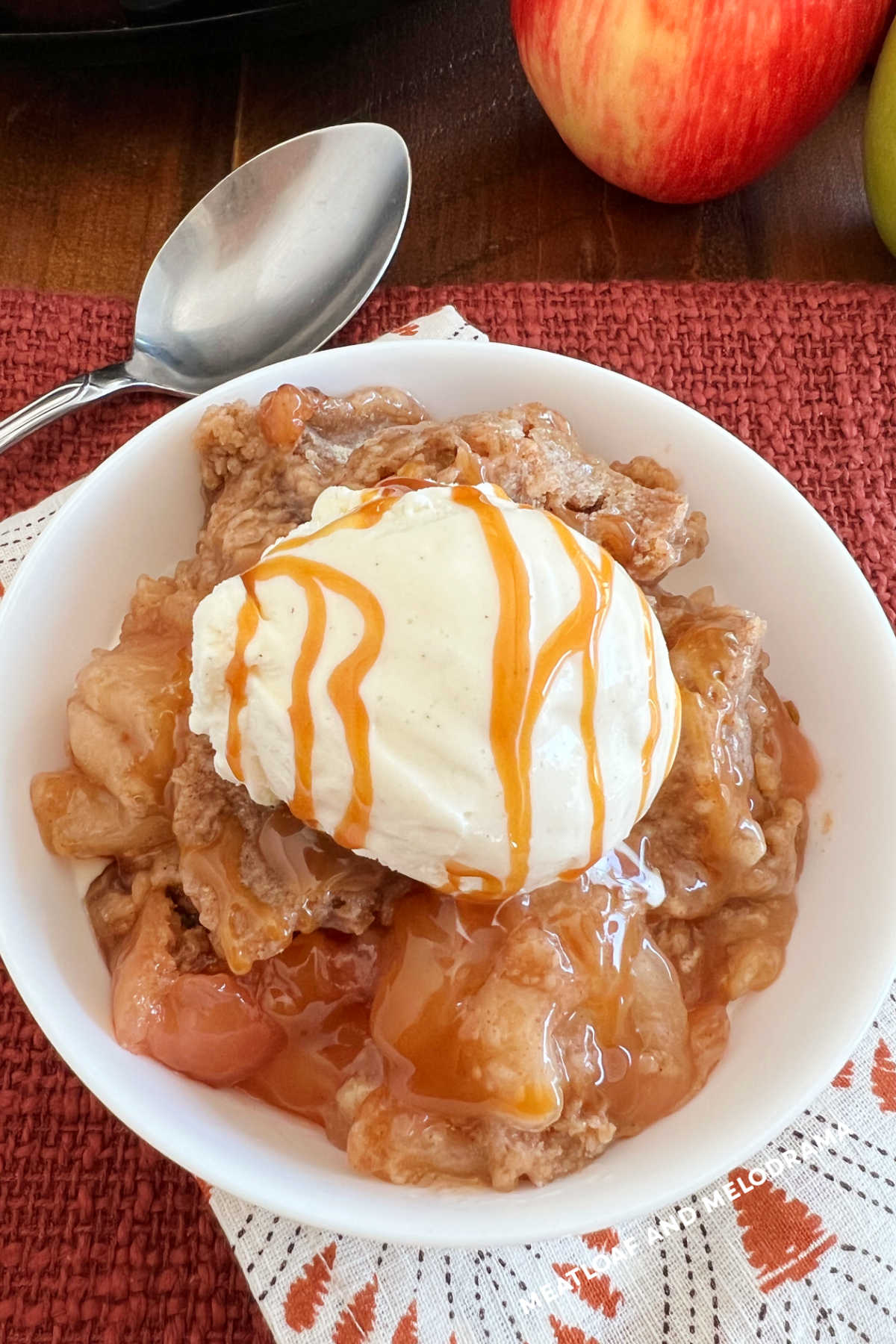 slow cooker apple cobbler with vanilla ice cream and caramel in bowl