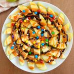 slices of caramel apple nachos with chocolate and candies on a platter