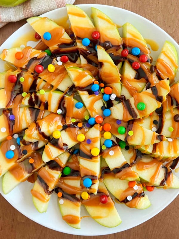 slices of caramel apple nachos with chocolate and candies on a platter