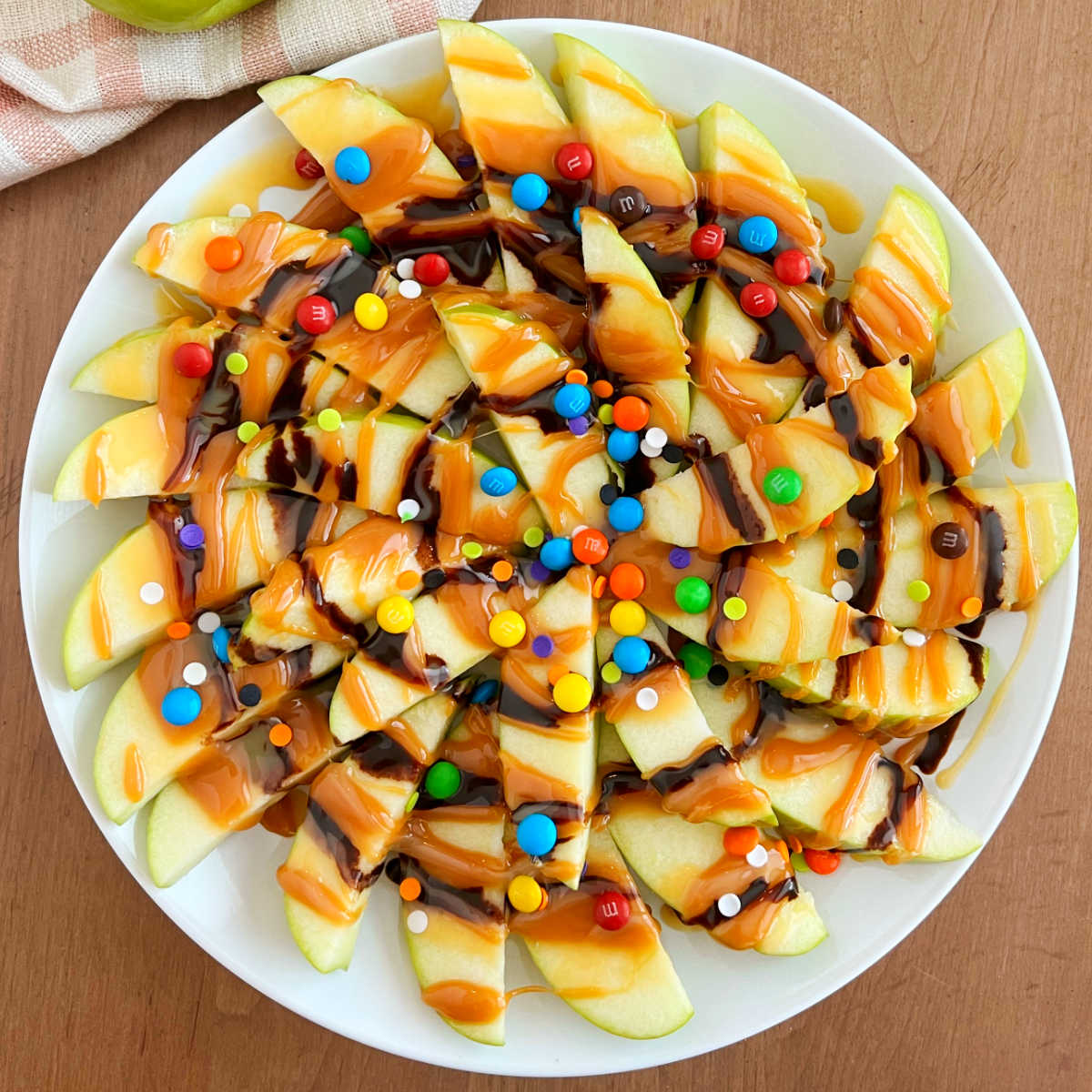 slices of caramel apple nachos with chocolate and candies on a platter