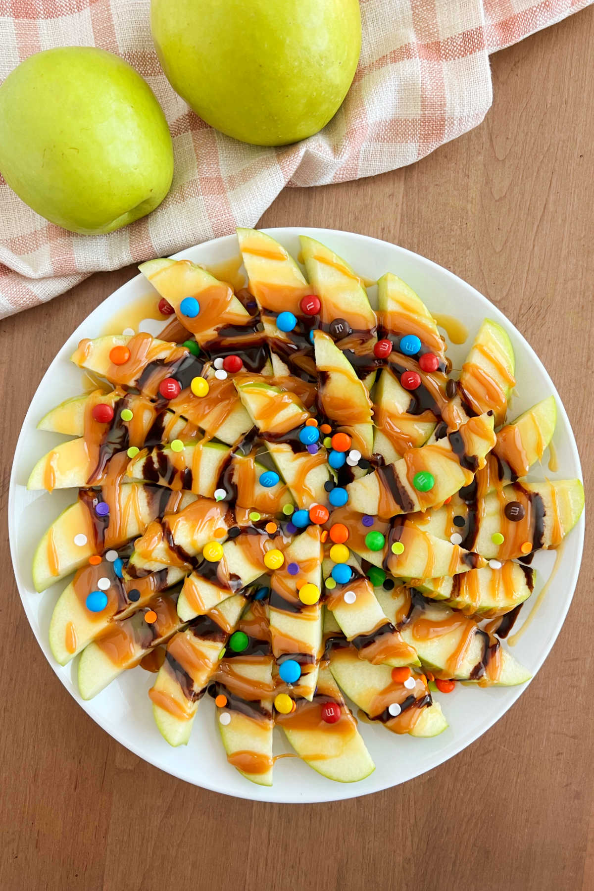 caramel apple slices with chocolate and candies served liked nachos on a platter