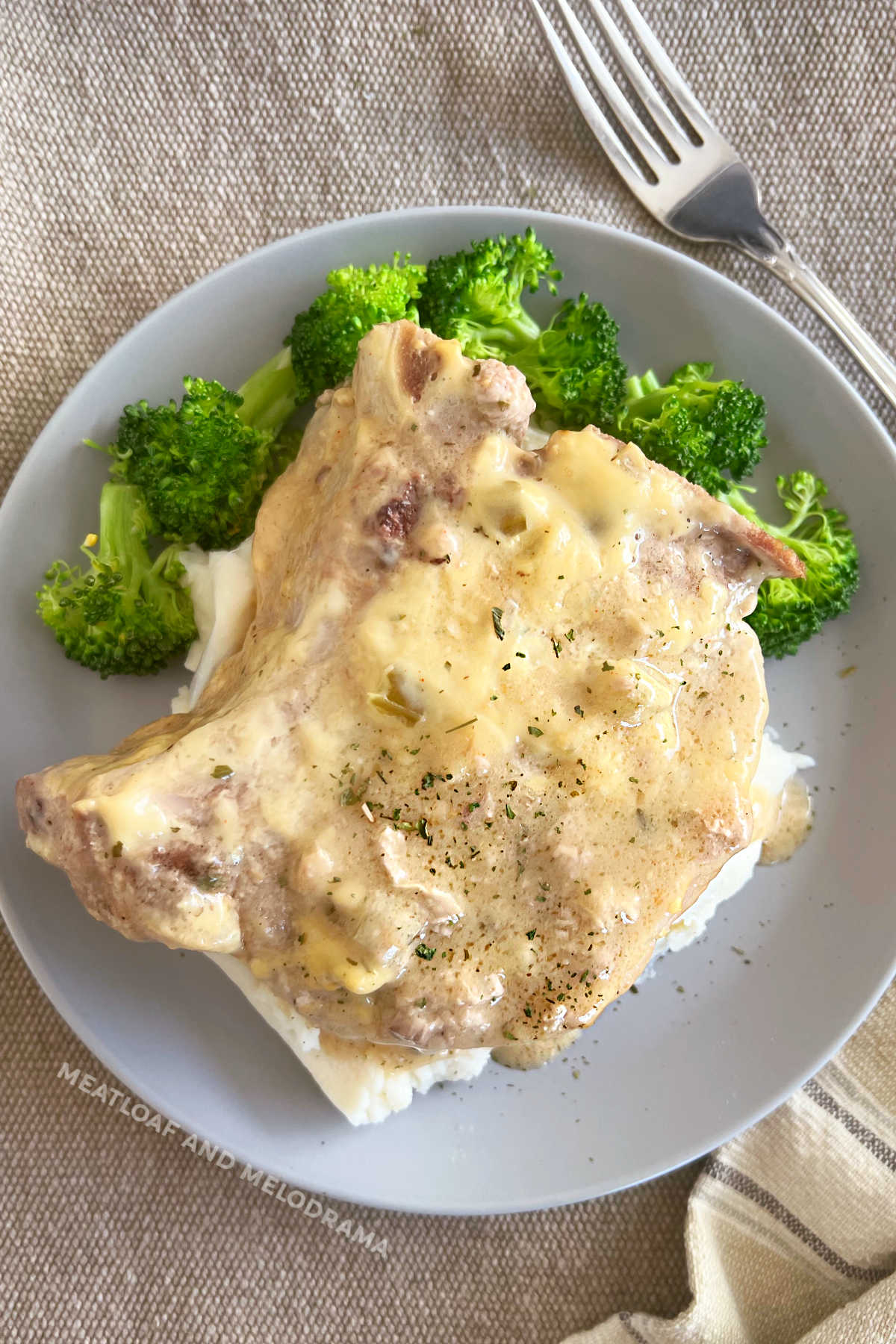 bone-in pork chop with creamy gravy over mashed potatoes and broccoli