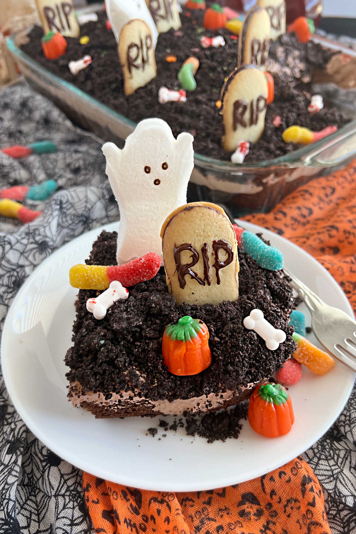 halloween dirt cake with gummy worms, tombstones and ghost on plate