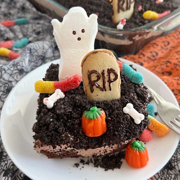 halloween dirt cake with crushed oreos, gummy worms, milano cookies and ghost on a plate