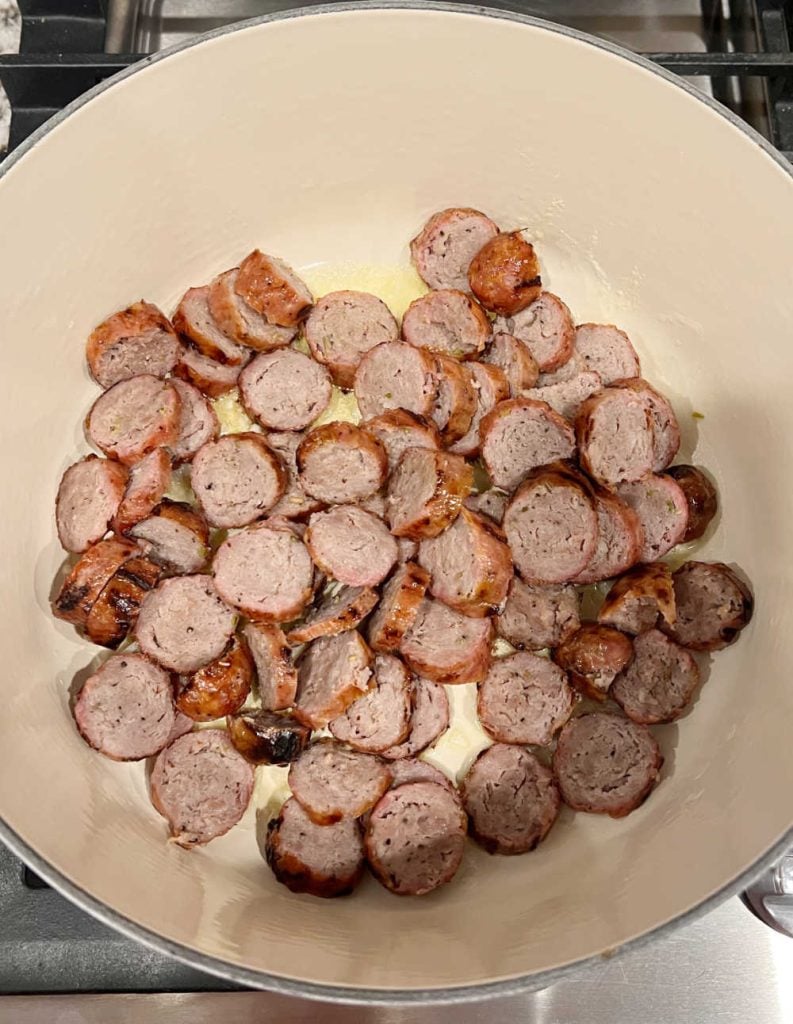 sliced Italian sausage with onions in Dutch oven
