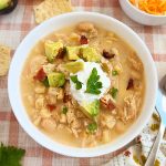 bowl of slow cooker white chicken chili with sour cream, bacon and avocado