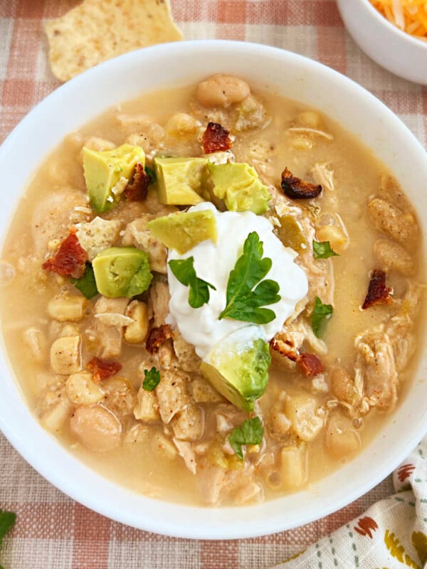 bowl of slow cooker white chicken chili with sour cream, bacon and avocado