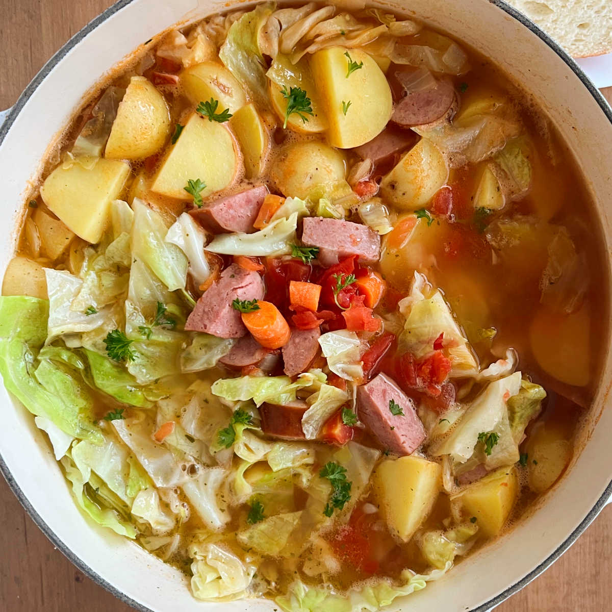 cabbage soup with sausage potatoes tomatoes and carrots in dutch oven
