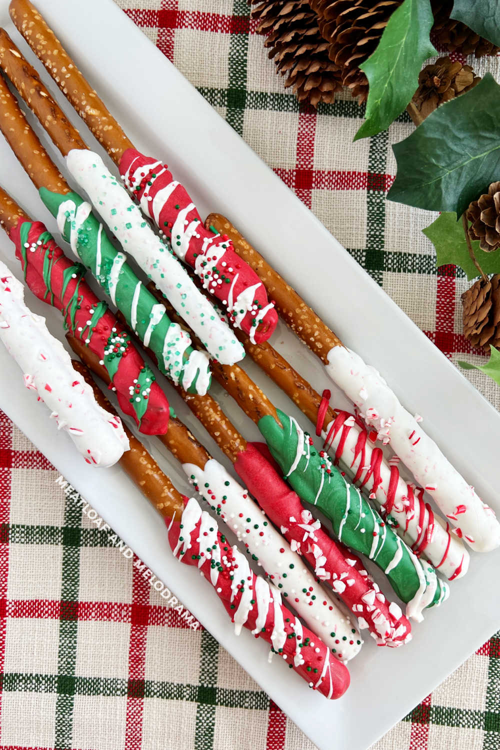 red, white and green chocolate covered Christmas pretzel rods on platter